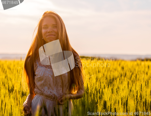 Image of Happy girl in wheat field at sunset