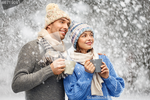 Image of happy couple in winter clothes with mugs