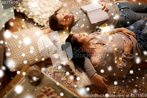 Image of happy couple with garland lying on floor at home