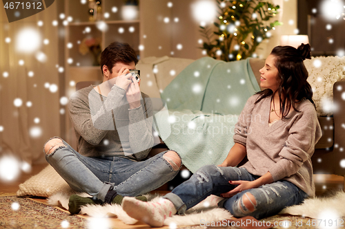 Image of happy couple with camera photographing at home