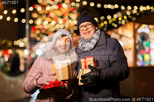 Image of happy senior couple with gift at christmas market