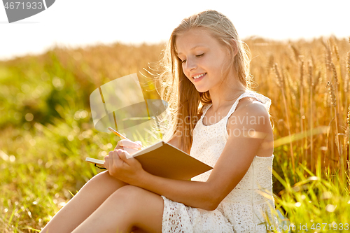 Image of smiling girl writing to diary on cereal field