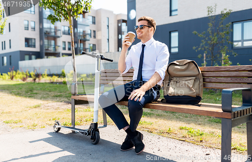 Image of businessman with scooter drinking coffee in city