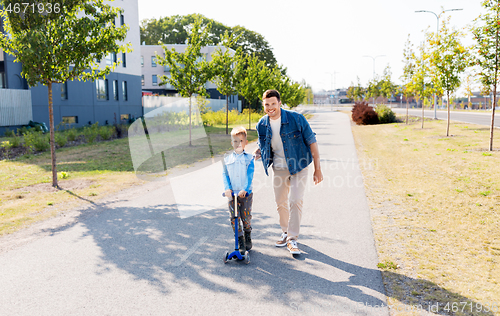 Image of happy father and little son riding scooter in city