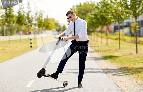 Image of young businessman riding electric scooter outdoors