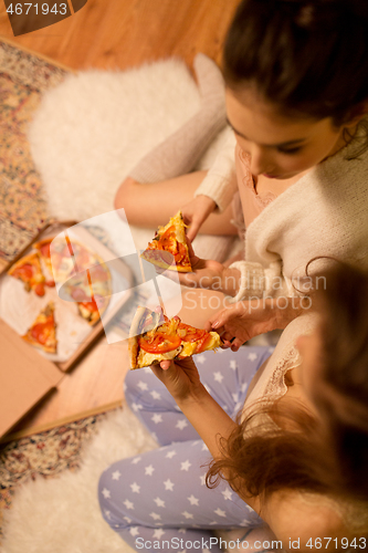 Image of happy female friends eating pizza at home