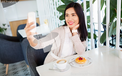 Image of asian woman taking selfie by smartphone at cafe