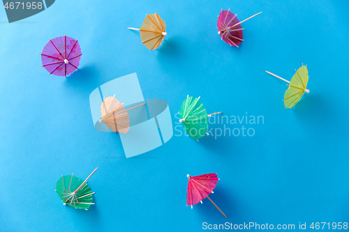 Image of cocktail umbrellas on blue background