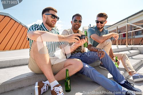 Image of men with smartphone drinking beer on street