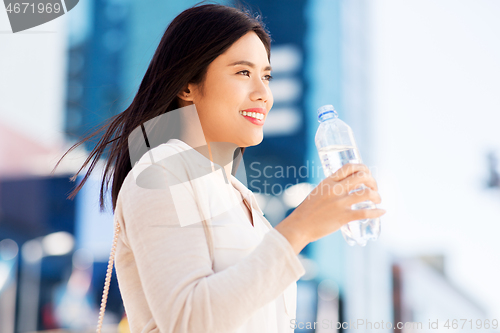 Image of asian woman drinking water from bottle in city