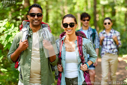 Image of group of friends with backpacks hiking in forest