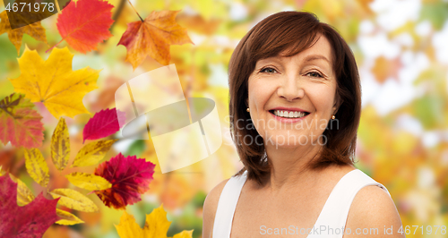 Image of portrait of happy senior woman over autumn leaves