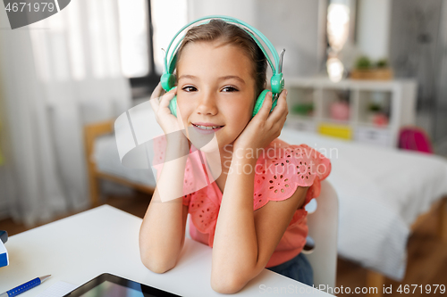 Image of girl in headphones with tablet computer at home