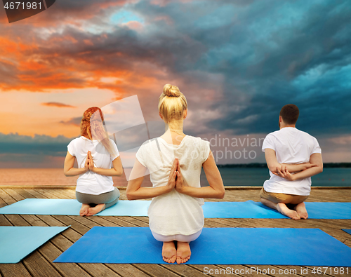 Image of group of people making yoga exercises outdoors