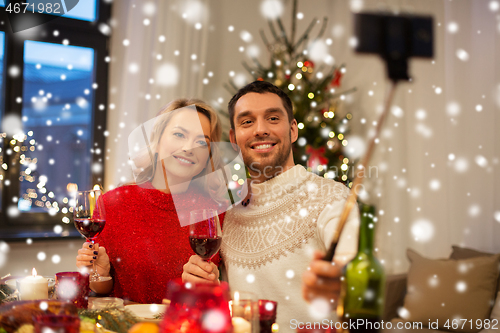 Image of couple taking picture by selfie stick at christmas