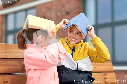 Image of school children with books having fun outdoors