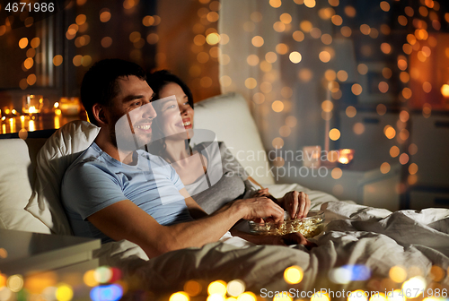 Image of couple with popcorn watching tv at night at home