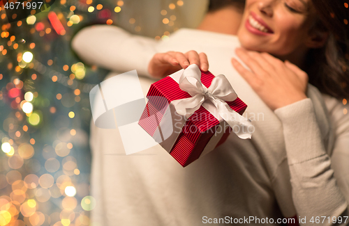 Image of close up of couple with christmas gift hugging