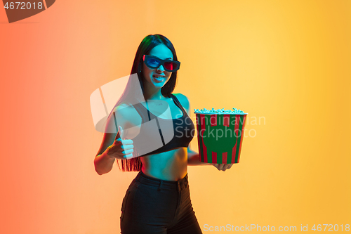 Image of Young woman\'s portrait on yellow-orange studio background in neon light