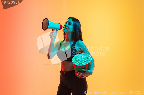 Image of Young woman\'s portrait on yellow-orange studio background in neon light