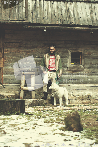 Image of hipster with dog in front of wooden house