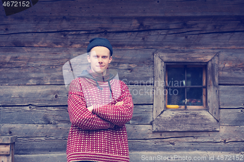 Image of young hipster in front of wooden house