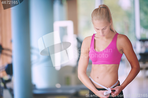 Image of young fit woman measuring belly