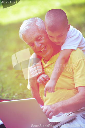 Image of grandfather and child using laptop