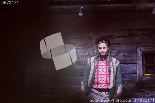 Image of portrait of young hipster in front of wooden house