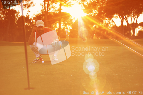 Image of golf player aiming perfect  shot on beautiful sunset