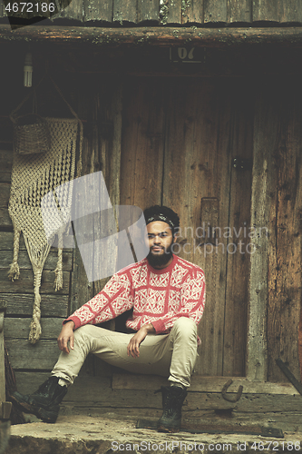 Image of portrait of young hipster in front of wooden house