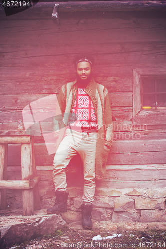 Image of portrait of young hipster in front of wooden house