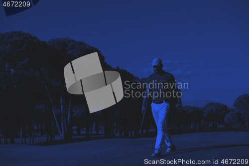 Image of golf player walking and carrying driver