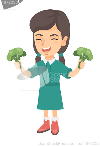 Image of Caucasian girl laughing and holding broccoli.