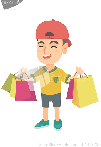 Image of Happy caucasian boy holding shopping bags.