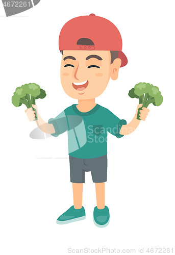 Image of Little caucasian boy laughing and holding broccoli