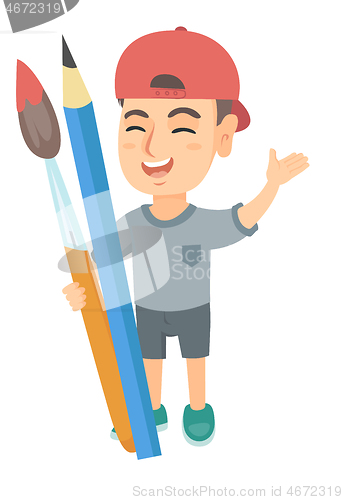 Image of Smiling boy holding big pencil and paintbrush.