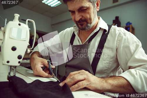 Image of Sewing process of the leather belt. Old Man\'s hands behind sewing.