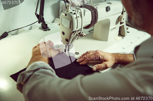 Image of Sewing process of the leather belt. old Man\'s hands behind sewing.