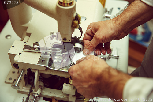 Image of Sewing process of the leather belt. old Man\'s hands behind sewing.