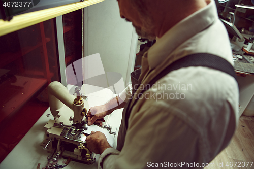 Image of Sewing process of the leather belt. old Man\'s hands behind sewing.