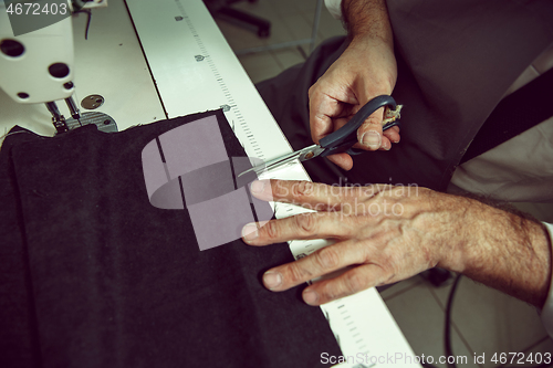 Image of Sewing process of the leather belt. old Man\'s hands behind sewing.