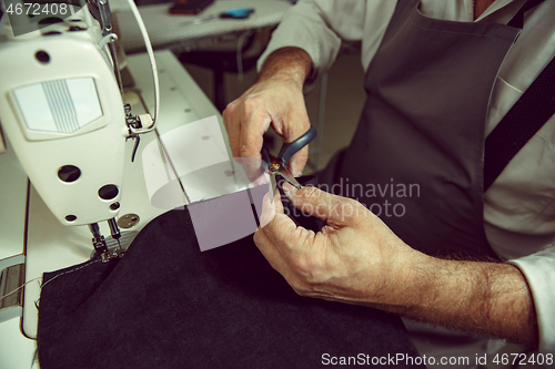 Image of Sewing process of the leather belt. old Man\'s hands behind sewing.