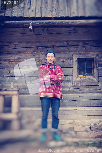 Image of young hipster in front of wooden house