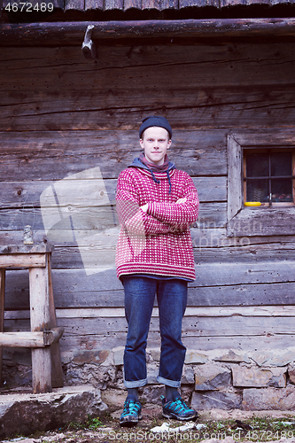 Image of young hipster in front of wooden house