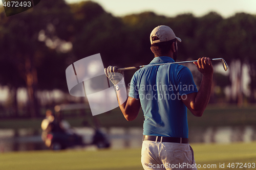 Image of golfer from back at course looking to hole in distance