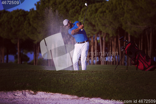 Image of golfer hitting a sand bunker shot on sunset