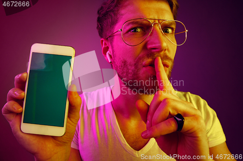 Image of Indoor portrait of attractive young man holding blank smartphone