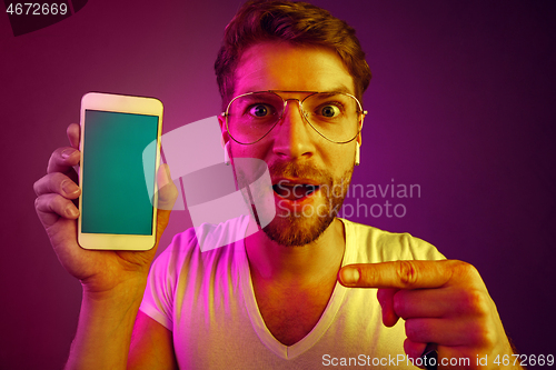 Image of Indoor portrait of attractive young man holding blank smartphone