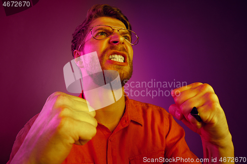 Image of The young emotional angry man screaming on pink studio background